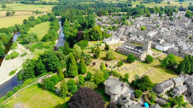 The image depicts a quaint, picturesque village nestled among lush greenery and rolling hills, with a serene river meandering through the landscape.AI-generated content may be incorrect.